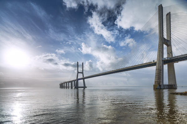Blue sky and the colors of dawn emphasize the architecture and atmosphere at the Vasco Da Gama Bridge Lisbon Portugal Europe