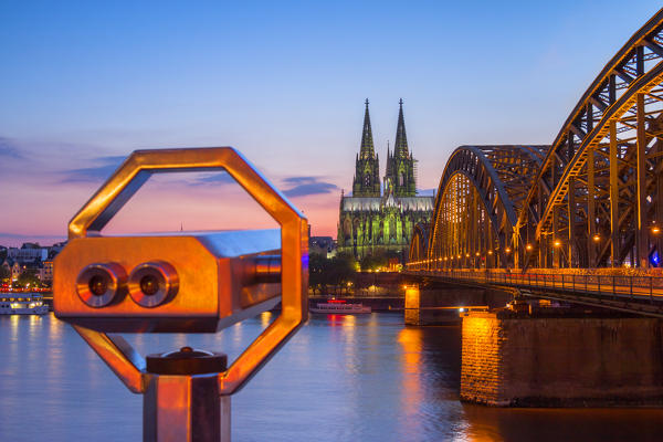 Hohenzoller Bridge over River Rhine and Cologne Cathedral with binoculars at dusk in Cologne city. Cologne city (Koln), North Rhine Westphalia, Germany, Europe. 