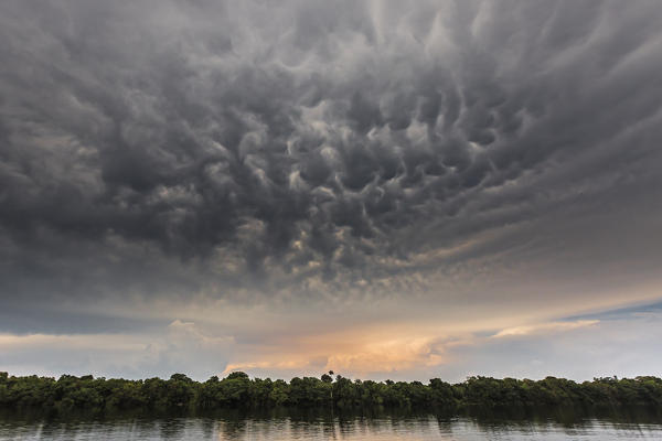 Rio negro waters depicted at sunset, with a strange cloud formation in the sky. Amazonas, Manaus, Brazil, South America.
